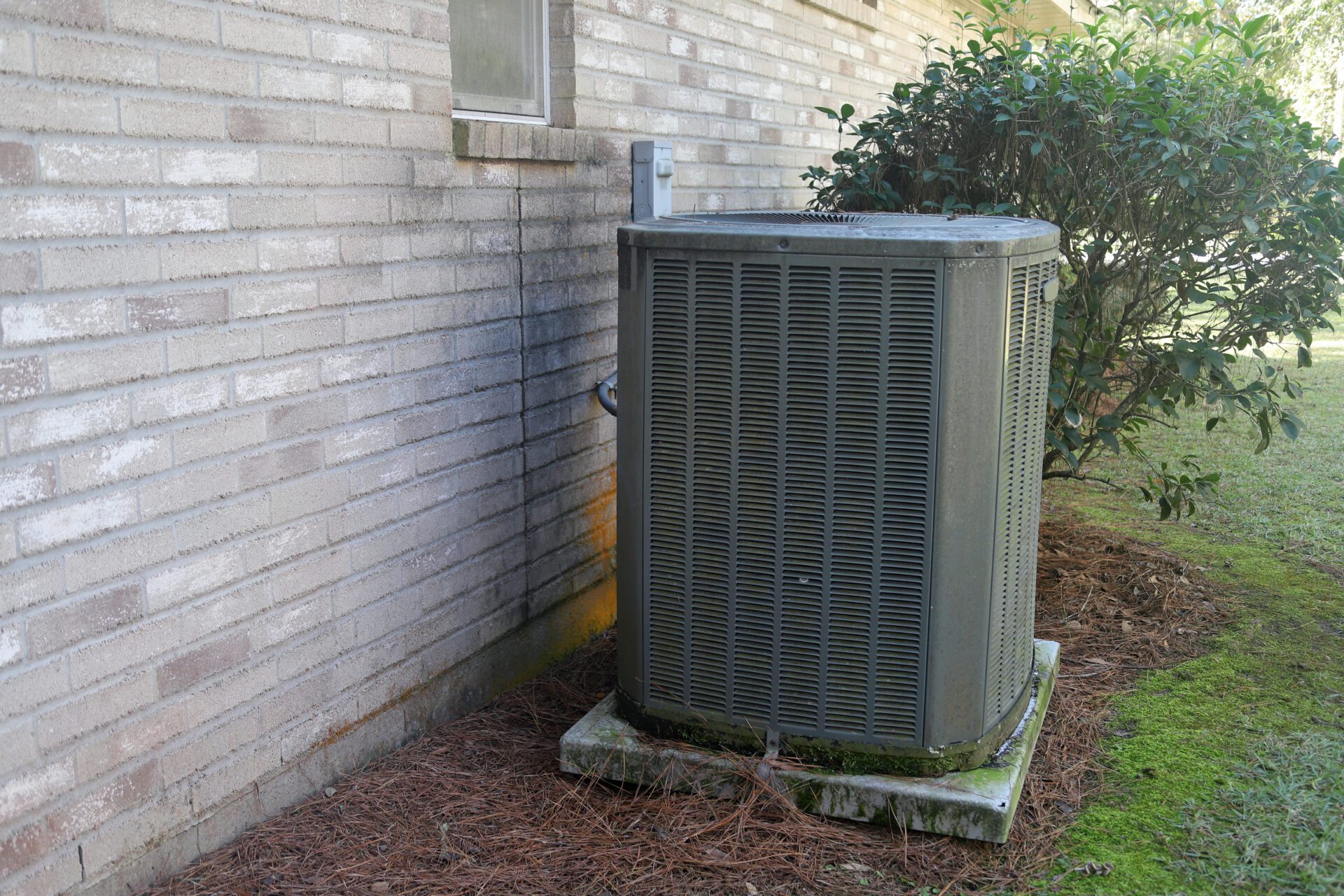 Air Conditioner Unit next to brick home