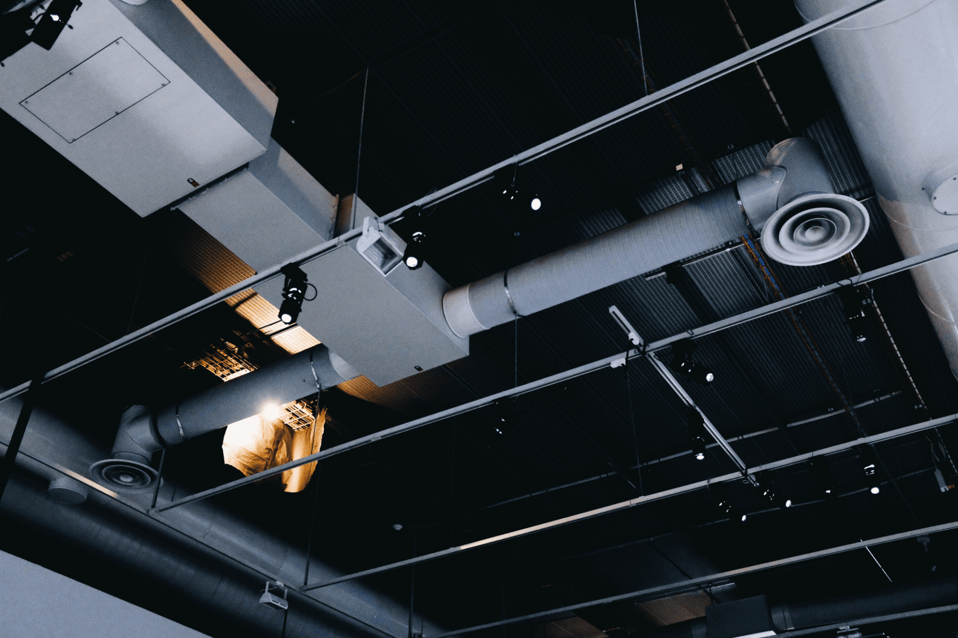 low angle shot of a metal black ceiling with white ventilation pipes